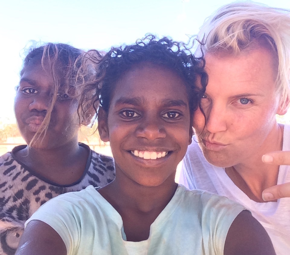 A close up image of three females looking at a camera. Two are girls with brown hair, brown skin and big smiles and one older blonde woman pouting.