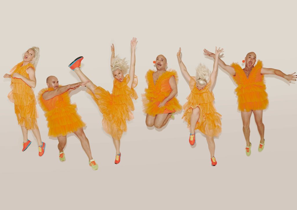Two people in orange dresses are repeated jumping, smiling and moving